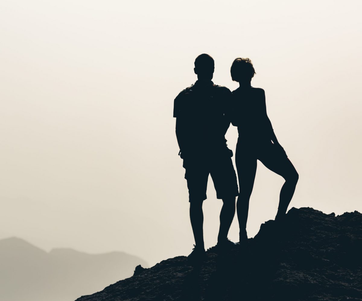 Couple celebrating, reaching life goal and love, business concept with man and woman looking at view. Motivational and inspirational silhouette landscape.
